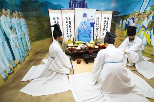 韓国人男性のグループが絵の前のテーブルに座っている。