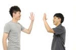 白い背景に韓国から来た2人のアジア人男性が互いにハイタッチをしている。