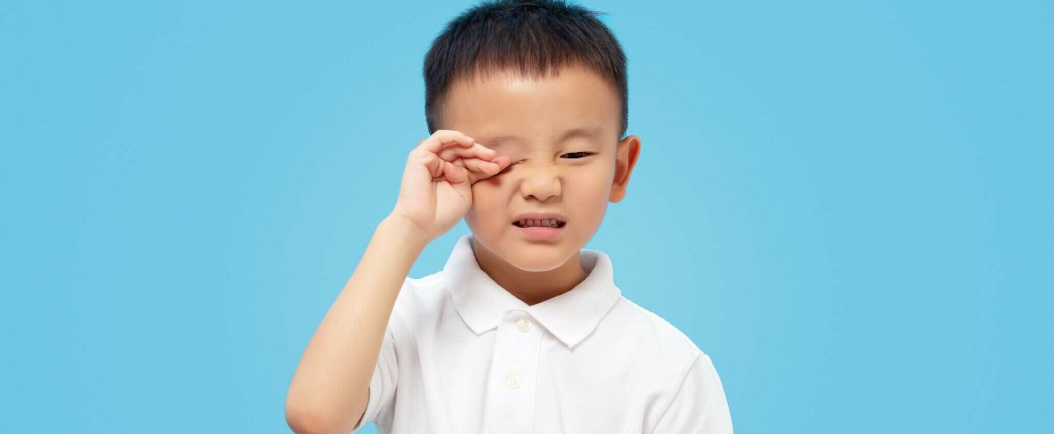 目に手を当てたアジア系の韓国人の少年。