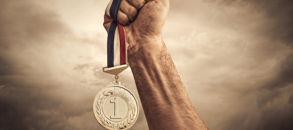 韓国の曇った背景に金メダルを持つ男性の手。 韓国の曇った背景に金メダルを持つ男性の手。