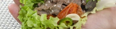 肉が入った韓国のレタス包みを持つ人の手。