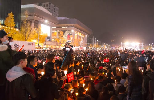 夜の韓国でキャンドルを持った人々の群衆。 夜の韓国でキャンドルを持った人々の群衆。