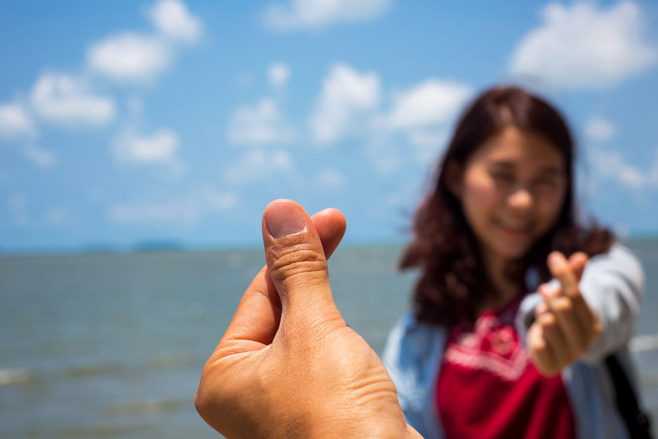 韓国の女性がビーチで少女の手を指さしている。