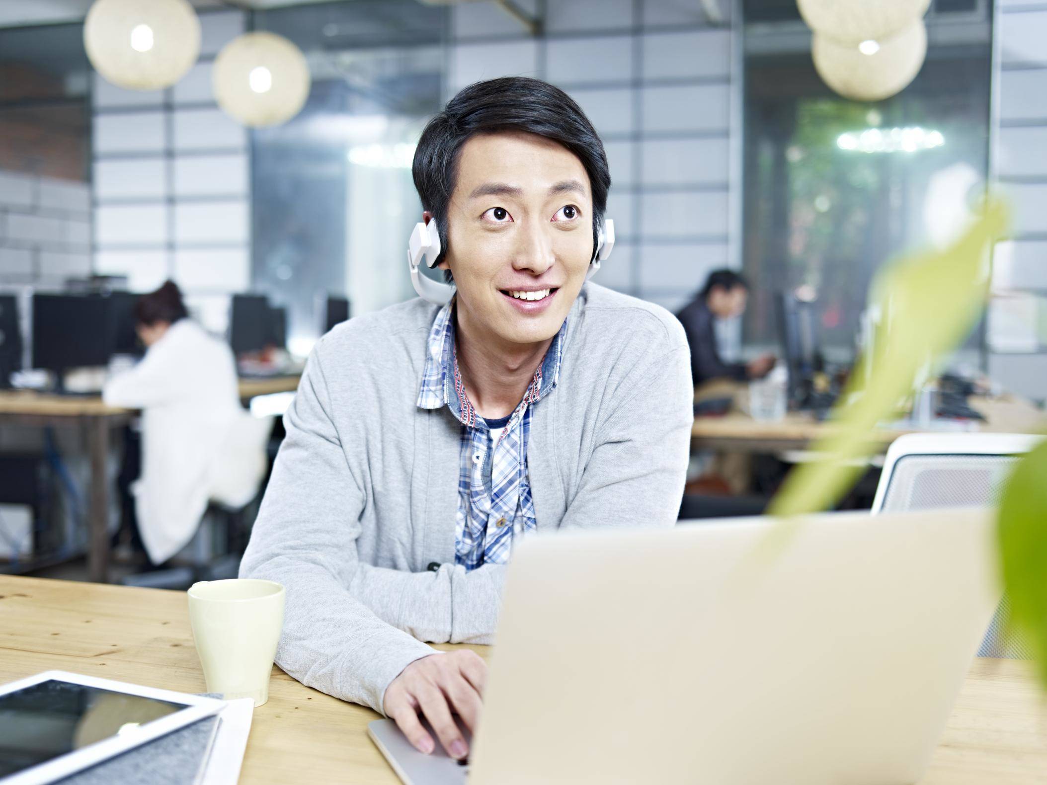 オフィスでラップトップを使用している若い韓国人男性。