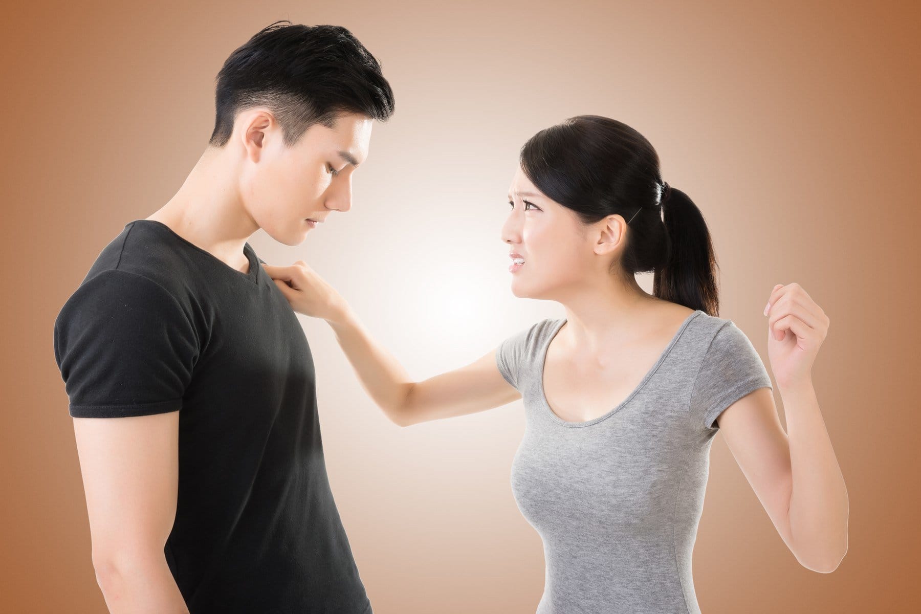 韓国の茶色の背景の前で議論する男性と女性。