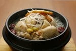 韓国料理からインスピレーションを得た、木製のテーブルに鶏肉が入った丼。