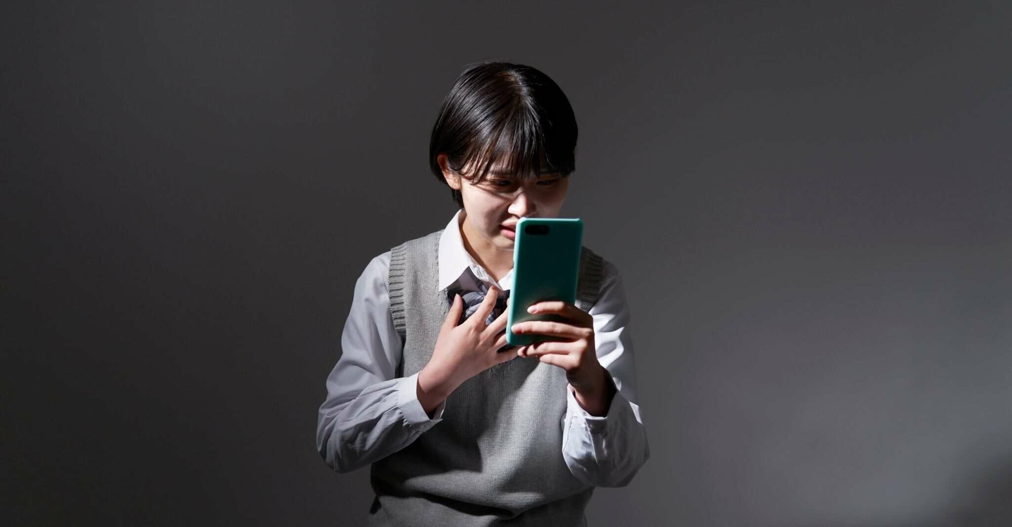 暗い背景の前で携帯電話を持っている韓国の女の子。