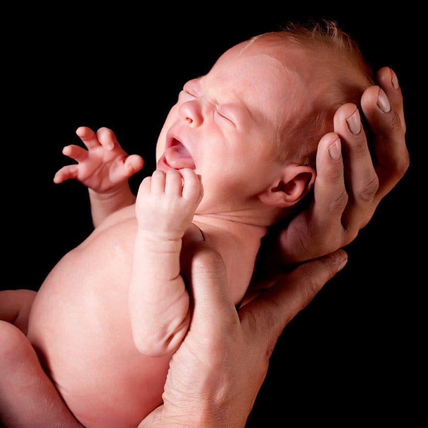 韓国で赤ちゃんが誰かの手に抱かれている。