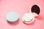 ピンクの背景にコンパクトなパウダーコンパクト。