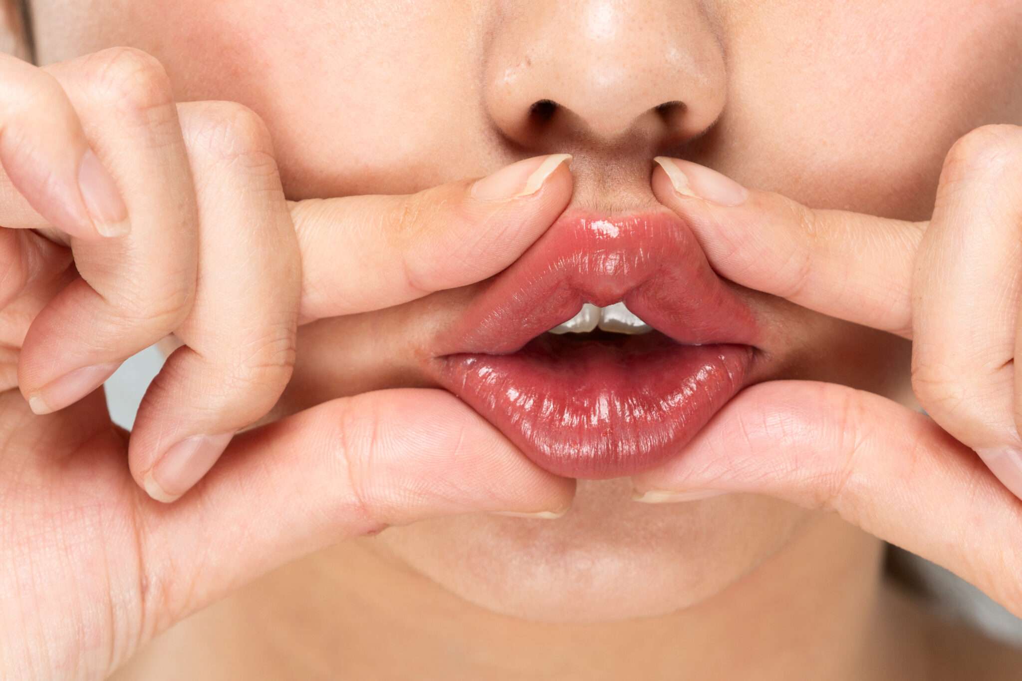 指が唇に触れている女性の口。
