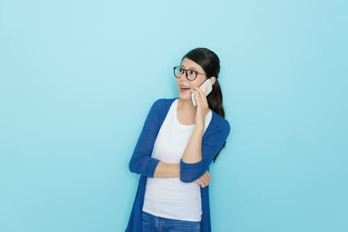 韓国で青い背景に電話で話す眼鏡をかけた女性。 韓国で青い背景に電話で話す眼鏡をかけた女性。