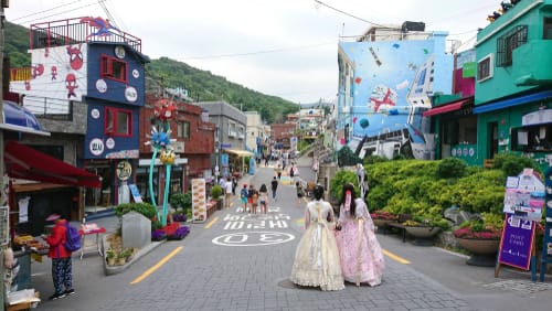 韓国のカラフルな建物が立ち並ぶ通りを2人の女性が歩いている。 韓国のカラフルな建物が立ち並ぶ通りを2人の女性が歩いている。