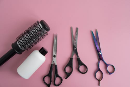 韓国風のピンクの背景にはさみ、櫛、ボトル。