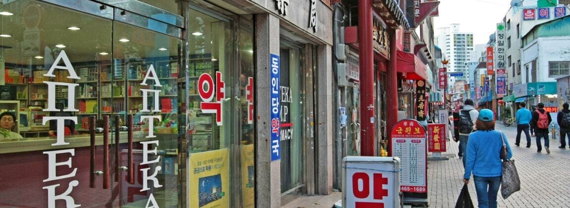 店先のある歩道を歩く韓国人女性。