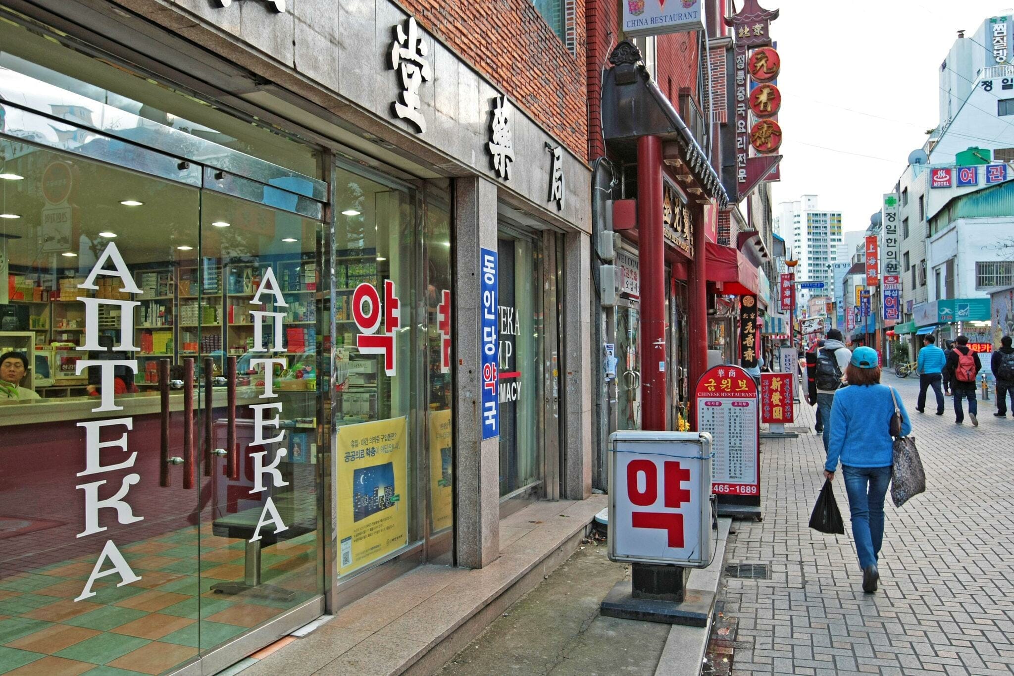 店先のある歩道を歩く韓国人女性。