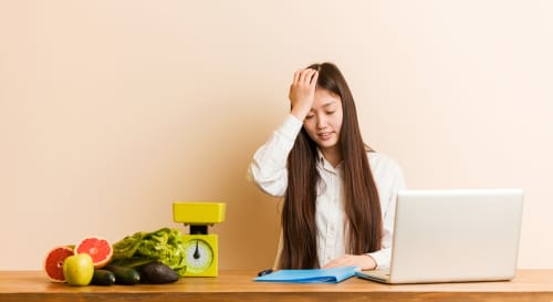 果物と野菜を持ったラップトップの前に座っている韓国の女性。