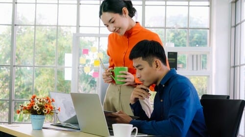 韓国で机に座ってラップトップで作業する男性と女性。