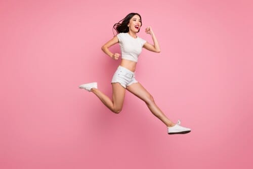 韓国のピンクの背景に若い女性がジャンプしている。 韓国のピンクの背景に若い女性がジャンプしている。