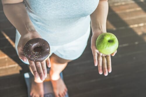韓国の秤の上にリンゴとドーナツを持つ女性。 韓国の秤の上にリンゴとドーナツを持つ女性。