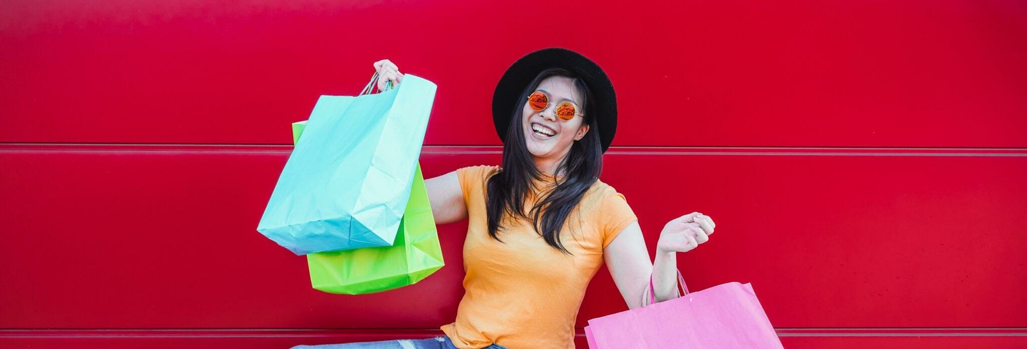 韓国の赤い壁の前で買い物袋を持つ女性。