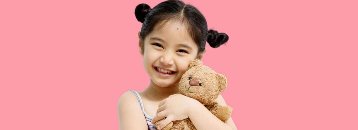 韓国のピンクの背景にテディベアを持つ小さな女の子。