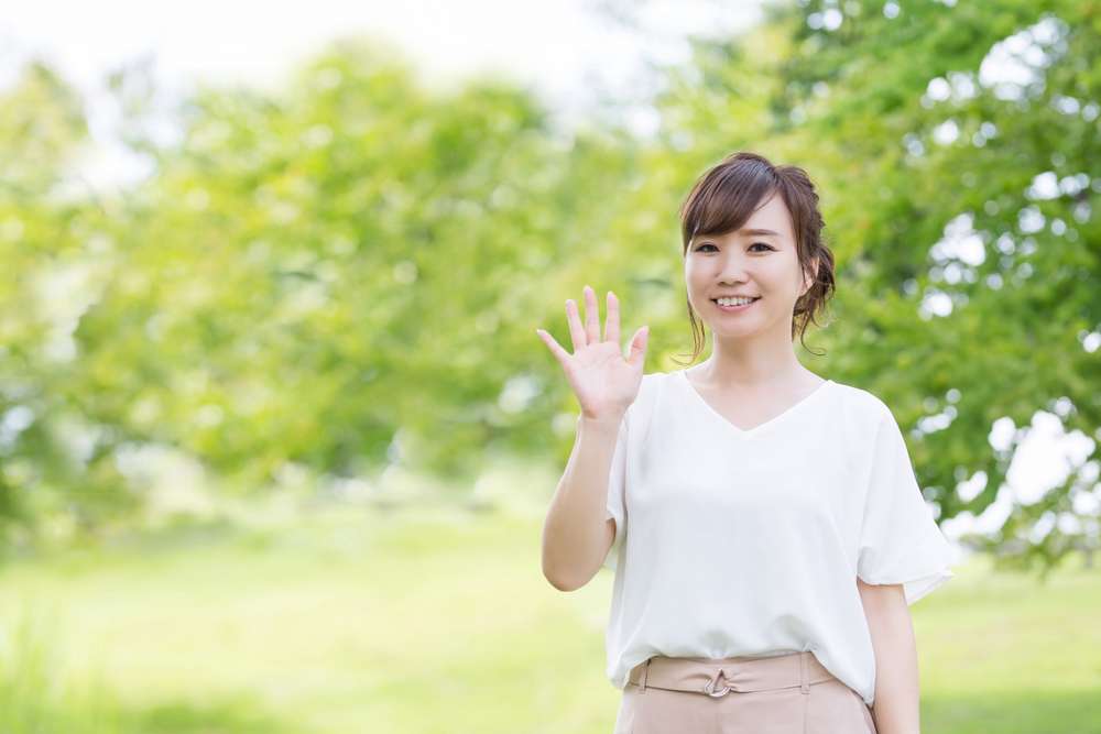 公園で手を振る韓国から来たアジア系の若い女性。