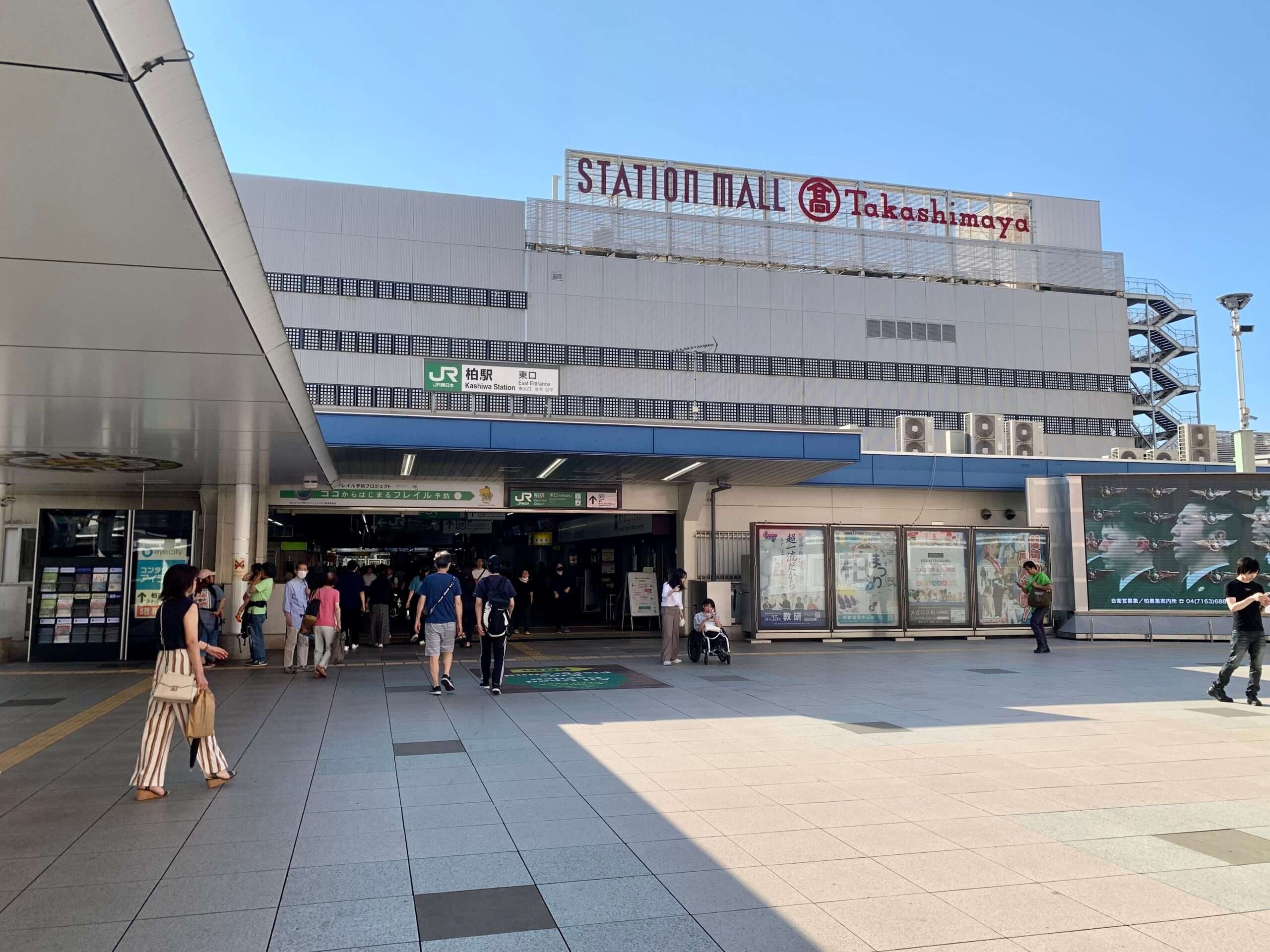 柏にある「ステーションモール」の看板が掲げられた大きな建物の外観。澄み切った青空の下、入り口の前を人々が歩いています。おそらく、中にある人気の韓国語教室を楽しむために向かっているのでしょう。