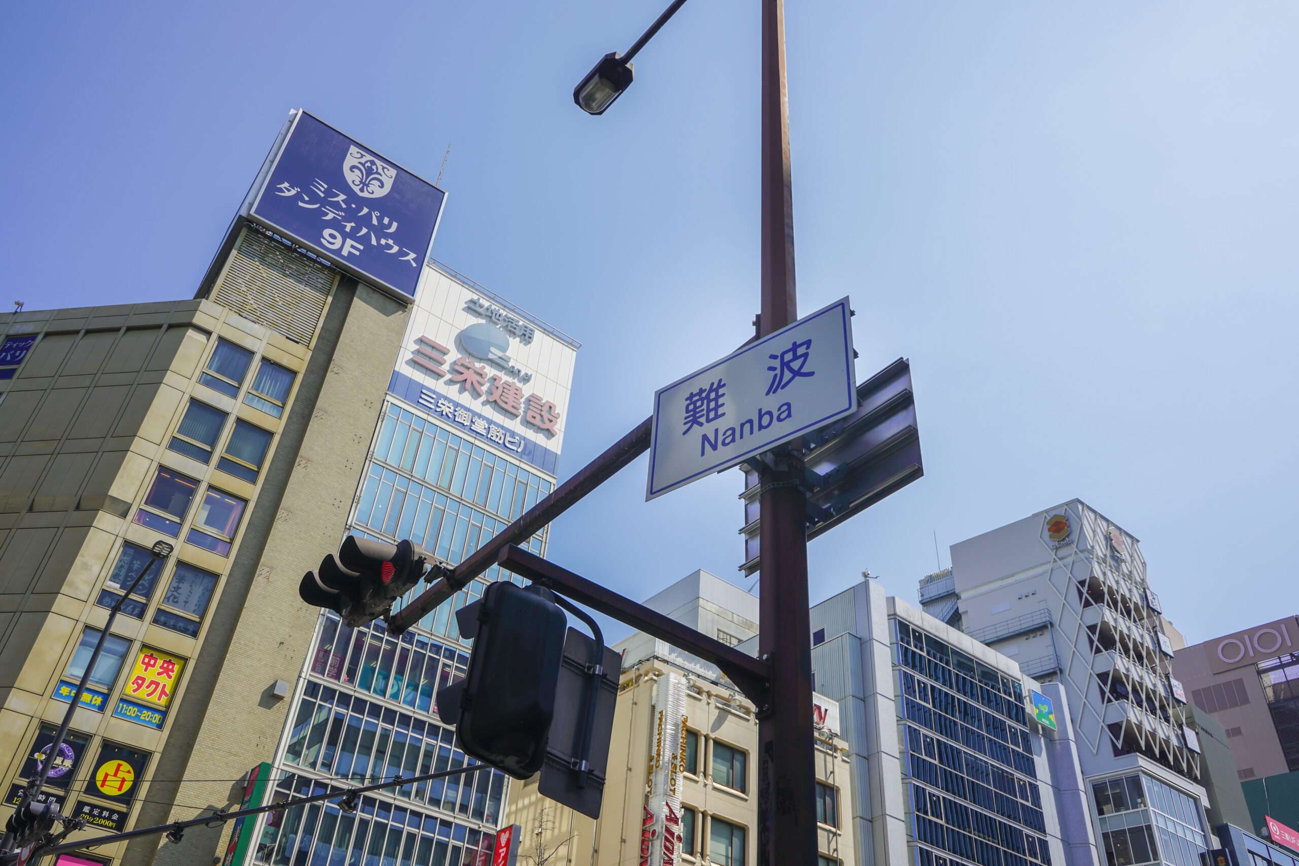 日本の難波の街並み。高層ビル、信号機、澄んだ青空が映えます。近くの韓国語教室では、地元の人や観光客に韓国語のレッスンを提供しています。