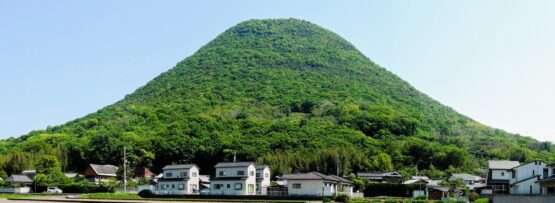 香川・高松の小さな村の背後には、青々とした円錐形の丘がそびえ立ち、前景には澄んだ青空の下、田畑が広がっています。近くの韓国語教室では、好奇心旺盛な住民に文化交流や語学レッスンを提供しています。