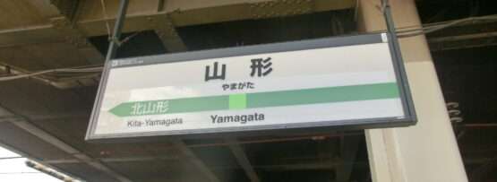 駅の標識には大きな金属製の天井の下に「山形」と「北山形」の文字が表示されており、山形・米沢の文化と、近くにある韓国語教室のような現代的な要素の融合を思い起こさせます。