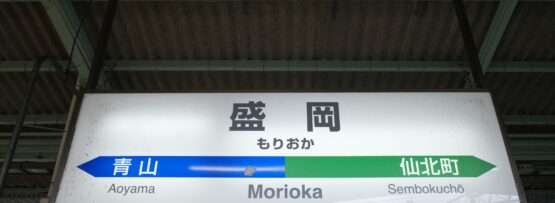 盛岡駅では、金属パイプと波形の屋根を背景に、旅行者に青山と仙北町への案内標識が設置されています。岩手・盛岡にあるこの環境は、地元の魅力と近くの韓国語教室のような国際的な機会を融合させています。