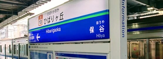 駅の標識には、ひばりヶ丘という駅名と、その上に案内記号、その下に地図が表示されており、列車は線路に沿って滑るように走っています。.