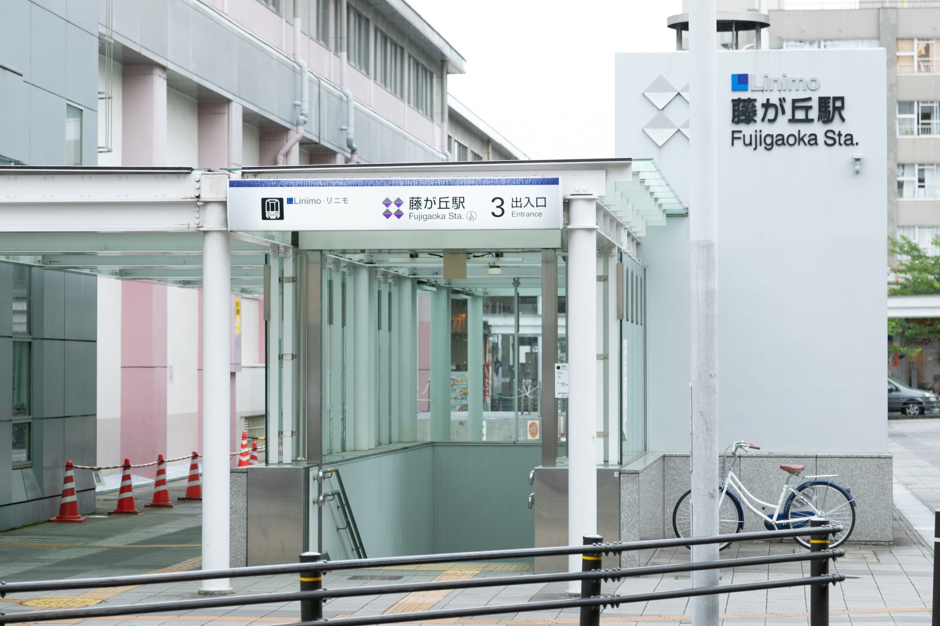 藤が丘駅の入り口には、自転車ラック、屋根付き通路、日本語と英語の駅標識があります。.