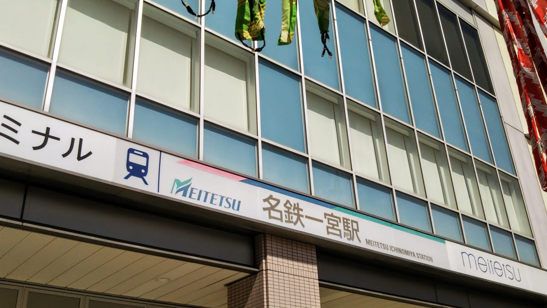 名鉄一宮駅の外観には、名鉄のロゴが目立つ日本語と英語の表記が設置されています。この賑やかな一宮の拠点では、窓が光を美しく反射し、旅行者から近くの韓国語教室マンマンツーについて問い合わせを受けることもあります。.