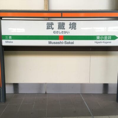 武蔵境の駅名標。左側に三鷹、右側に東小金井の方向が日本語と英語で書かれています。近くで次回の韓国語教室マンツーマンセッションに向かう人に最適です。.