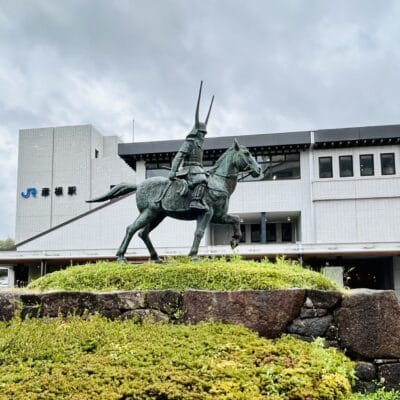 彦根・滋賀では、曇り空の下、豊かな緑に囲まれた駅前に堂々とした騎馬武者像が堂々と立っています。近くの韓国語教室マンツーマンでは、個人に合わせた語学クラスを提供し、地域に文化的な活気を与えています。.