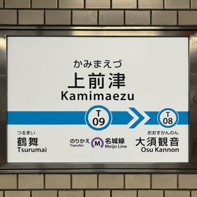 上前津駅 (T09) のタイル張りの壁に鶴舞 (T08) と大須観音への行き方を示す標識があり、近くにある乗り換えオプションがあり、上前津へ向かう通勤者や韓国語教室マンツーマンセッションに参加する人に最適です。.