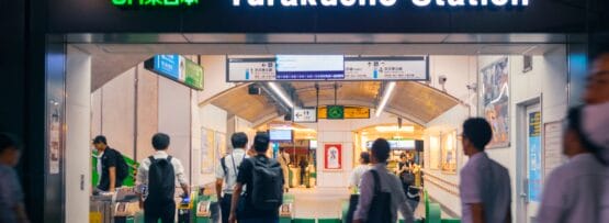 有楽町駅の改札を通る人々。上の駅名標は日本語とローマ字が併記されて点灯しています。近くの韓国語教室マンツーマンでは、マンツーマンで韓国語を学びたい人向けに個別の言語レッスンを提供しています。.