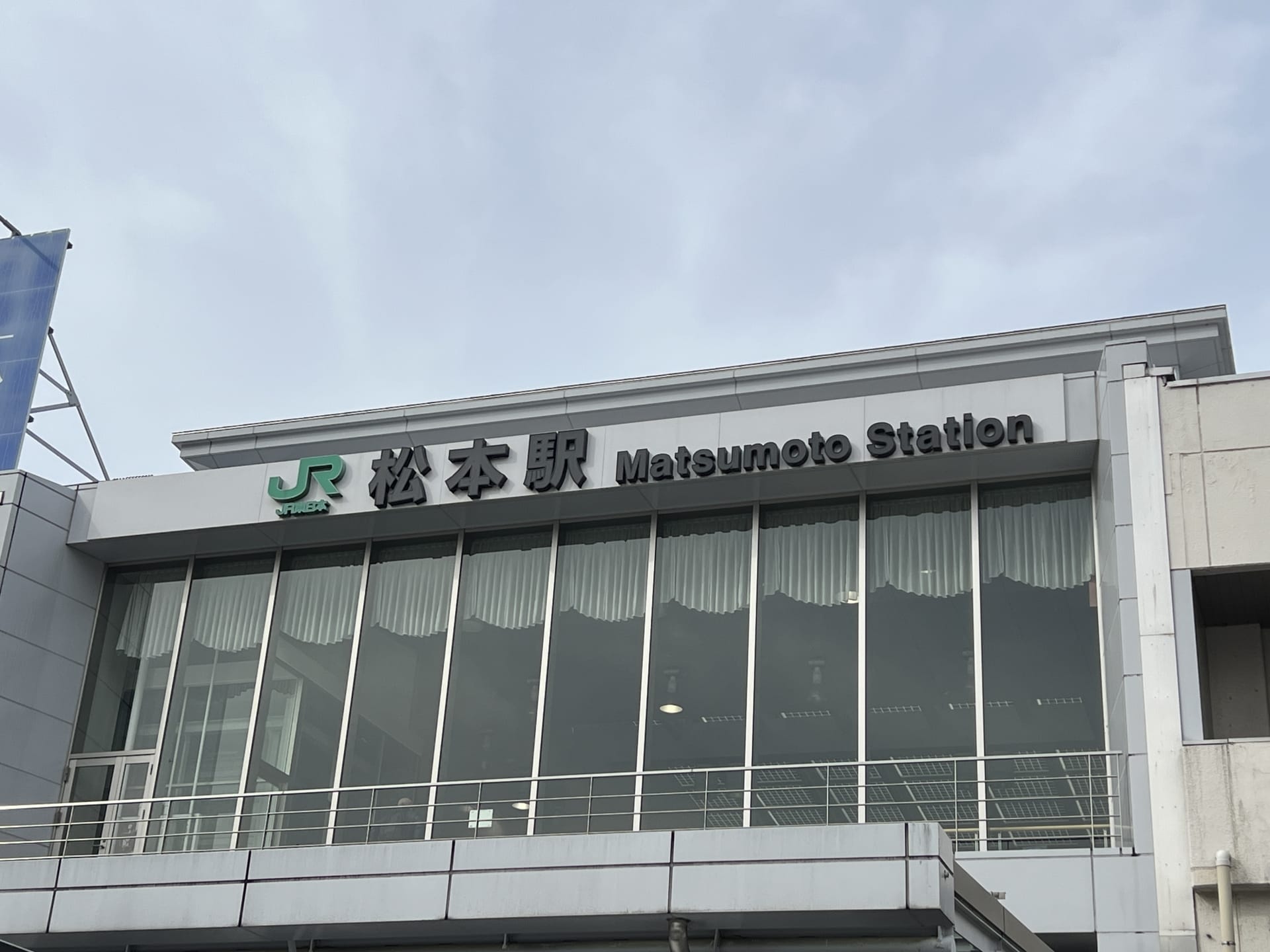 この画像は松本駅の外観を捉えたもので、日本語と英語の標識が掲げられており、韓国語教室マンツーマンに見られる個人的な配慮に似た活気に満ちた文化の融合を反映しています。.