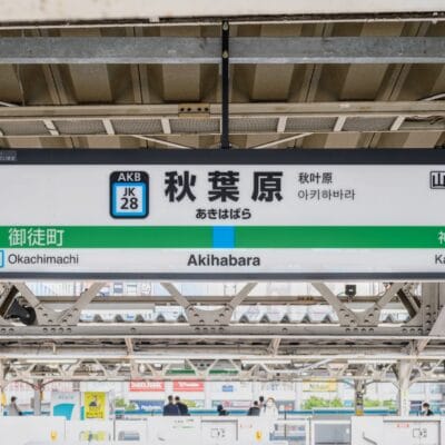 駅のプラットホームは活気に満ち、看板には英語、日本語、韓国語、中国語で「秋葉原」と誇らしげに表示されています。プラットホームの番号は旅行者を案内し、矢印は御徒町と神田を指しています。近くでは、熱心な学習者を待つ韓国語のマンツーマンクラスがあります。.