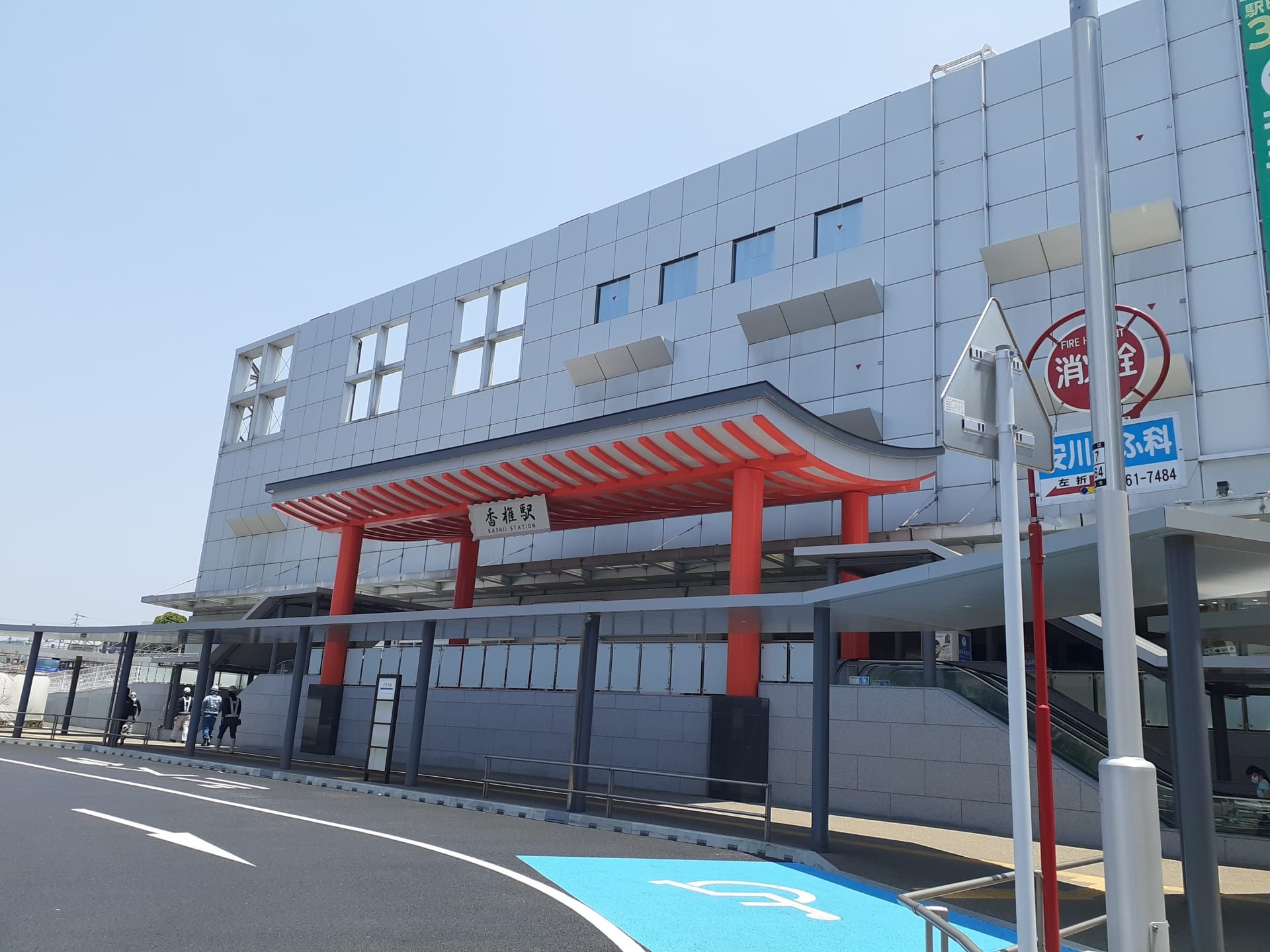 澄んだ空の下、赤い鳥居をイメージしたエントランスと正面の青い駐車場を備えたモダンな建物は、香椎の活気ある雰囲気に自然に溶け込んでいます。.