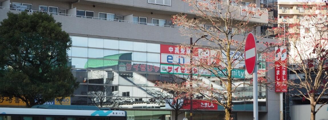 にぎやかな街路の風景には、東久留米や韓国語教室マンツーマンを宣伝するものなど、複数の日本語の看板が掲げられた建物とともに、葉の落ちた木々の間を通過するバスが捉えられている。. にぎやかな街路の風景には、東久留米や韓国語教室マンツーマンを宣伝するものなど、複数の日本語の看板が掲げられた建物とともに、葉の落ちた木々の間を通過するバスが捉えられている。.