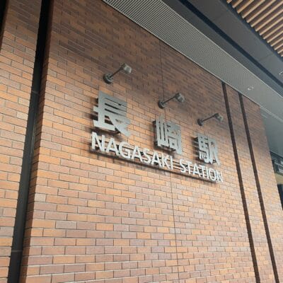 レンガの壁には、長崎の文字の横に、英語と日本語で「長崎駅」と書かれた標識が飾られている。.