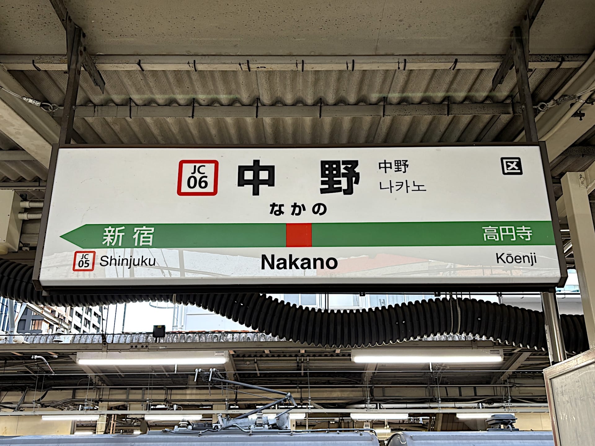 中野の駅標識には、新宿と高円寺への道順が示されており、駅コード JC06 とプラットフォームの詳細が示されています。近くには、韓国語の学習に興味がある人向けに個別のレッスンを提供する韓国語教室マンツーマンがあります。.