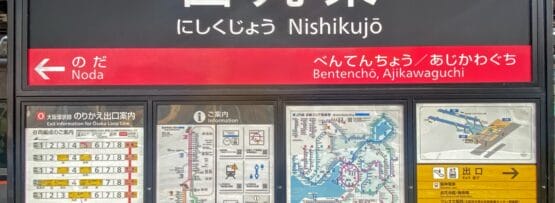 西九条の駅標識には、地図、電車の時刻表、日英二か国語の情報が誇らしげに表示されています。西九条エリアに近い便利な場所にあり、道順を探している旅行者や、近くで韓国語教室マンツーマンのセッションに参加している旅行者にわかりやすく提供します。.