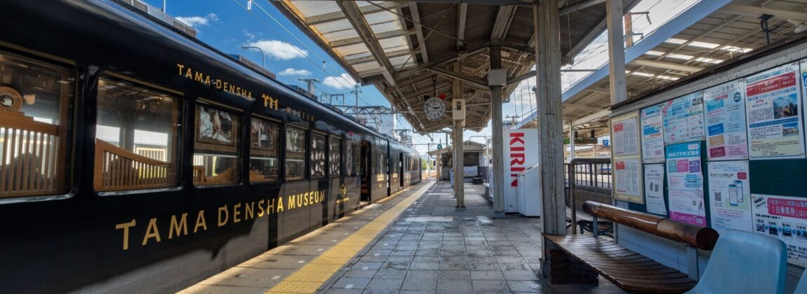 駅のホームには、左側に「たま電車ミュージアム」と書かれた黒い電車が停まっており、右側には大きなキリンの自動販売機が立っている。屋根付きの掲示板のそばには青い椅子が整然と並べられており、和歌山の穏やかな雰囲気を醸し出している。.