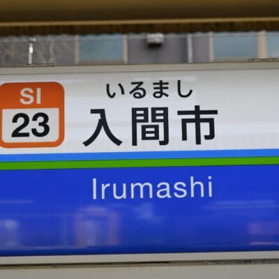 駅の標識には、駅コード SI 23 とともに、英語と日本語の両方で「入間市」と大きく表示されています。.