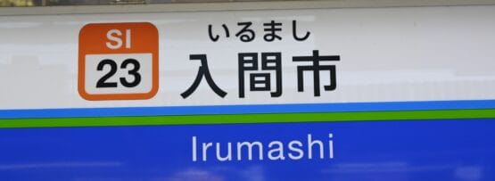 駅の標識には、駅コード SI 23 とともに、英語と日本語の両方で「入間市」と大きく表示されています。.