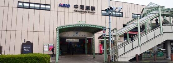 ベージュ色の外観と KEIO の看板が目印の中原駅の入り口には、手前に歩道と横断歩道へと続く階段があります。近くには、マンツーマンで学べる韓国語の個別クラスがあります。.