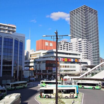 賑やかな高月市街地のバス停。高層ビルに囲まれ、澄み切った青空が広がる美しい風景です。.